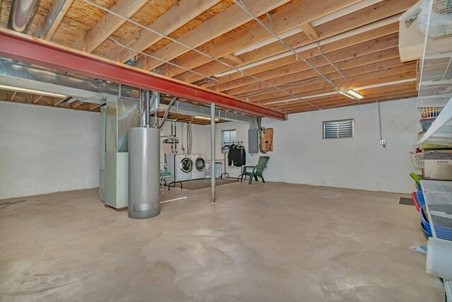 unfinished basement featuring heating unit, electric panel, water heater, and washer and dryer