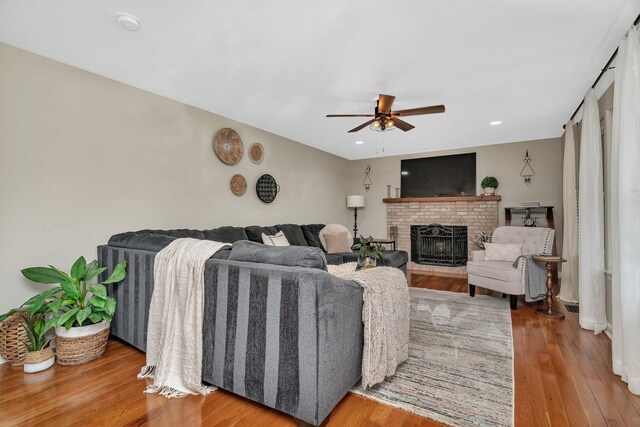 living area with ceiling fan, a fireplace, recessed lighting, and wood finished floors
