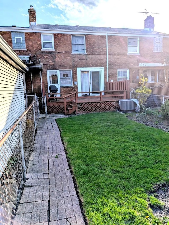 back of house with cooling unit, a lawn, a wooden deck, a fenced backyard, and brick siding