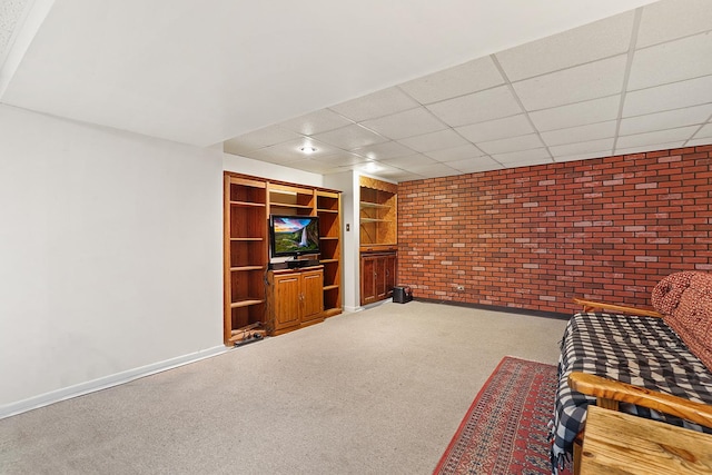 unfurnished room featuring a paneled ceiling, baseboards, brick wall, and carpet floors
