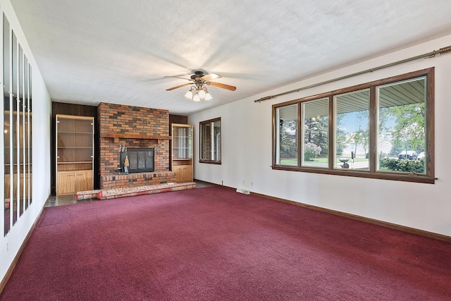 unfurnished living room with a ceiling fan, dark carpet, baseboards, and a fireplace