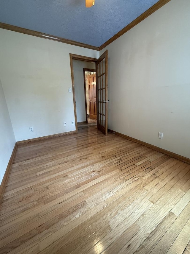 spare room with wood-type flooring, ornamental molding, baseboards, and french doors