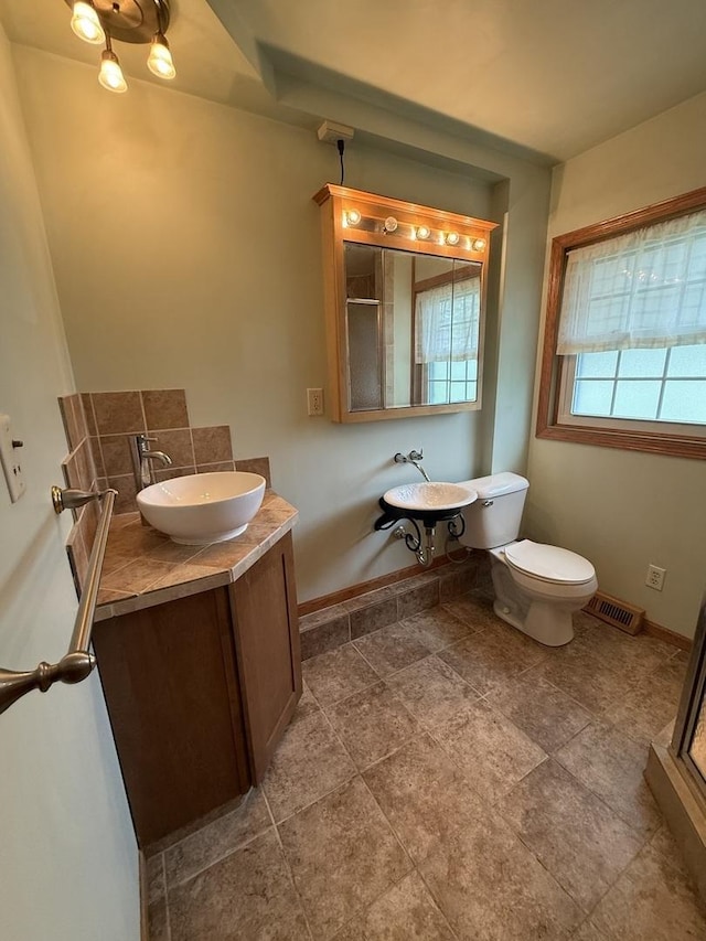 full bath featuring baseboards, a sink, a stall shower, and toilet