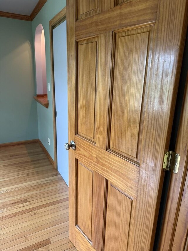interior details with arched walkways, baseboards, ornamental molding, and wood finished floors