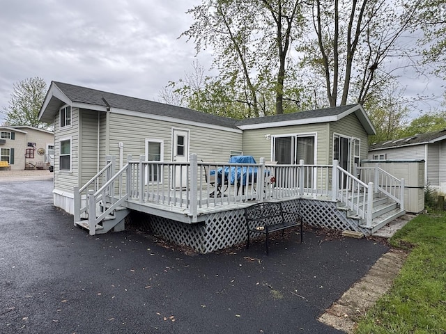rear view of house featuring a wooden deck and an outdoor structure