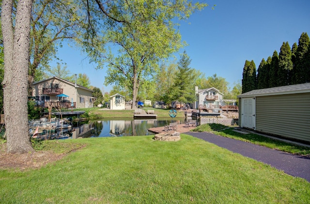 view of green lawn featuring a water view and an outbuilding