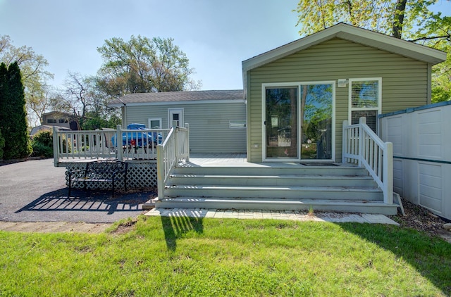 back of house with a deck and a lawn
