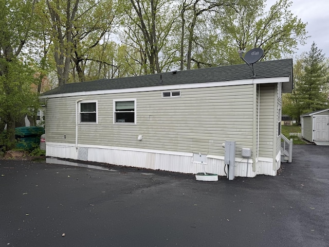 rear view of property featuring an outbuilding and a storage shed