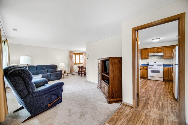 living room featuring visible vents, a baseboard radiator, baseboards, and light wood-type flooring