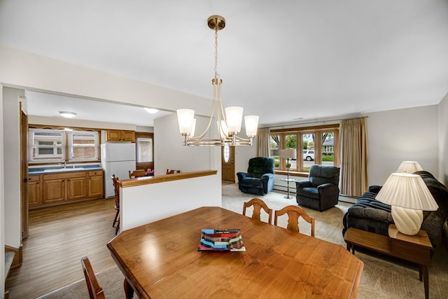 dining space featuring light wood-style floors, baseboard heating, and a chandelier