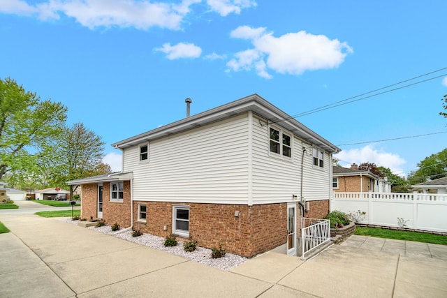 view of side of home with fence, a patio area, and brick siding