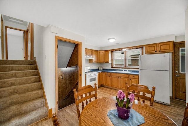 kitchen featuring white appliances, a sink, and light wood finished floors
