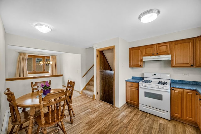 kitchen featuring light wood-style floors, a chandelier, brown cabinetry, white range with gas stovetop, and under cabinet range hood