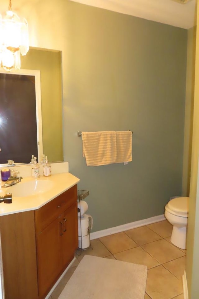 bathroom featuring tile patterned floors, toilet, vanity, baseboards, and a chandelier
