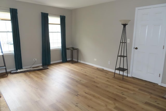 unfurnished room with light wood-type flooring and baseboards