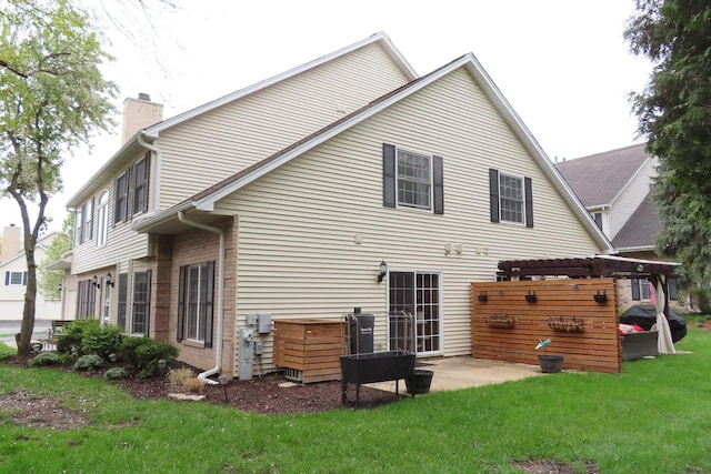 rear view of house with a chimney, a lawn, a pergola, and a patio