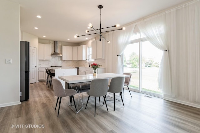 dining room with light wood-style floors, a chandelier, recessed lighting, and baseboards