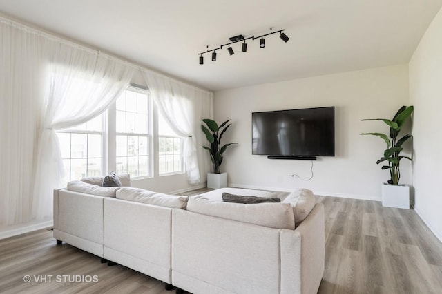 living room with rail lighting, wood finished floors, and baseboards