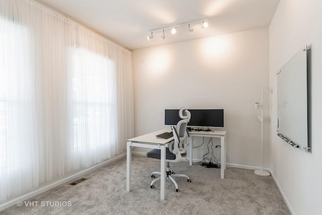 carpeted office featuring rail lighting and baseboards