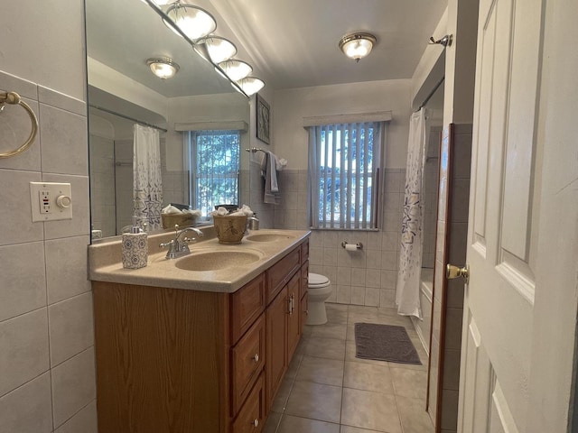bathroom with tile walls, tile patterned floors, double vanity, toilet, and shower / bath combination with curtain