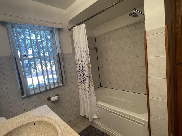 full bathroom with tile walls, a sink, a combined bath / shower with jetted tub, and tile patterned floors