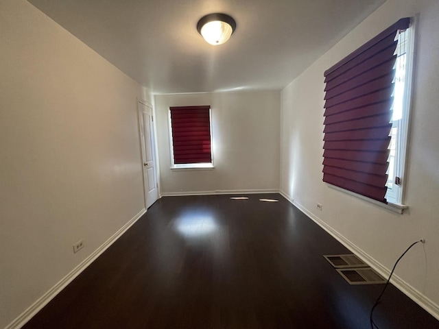 spare room with dark wood-style floors and baseboards