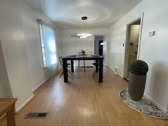 dining space with a chandelier, light wood-style floors, and baseboards