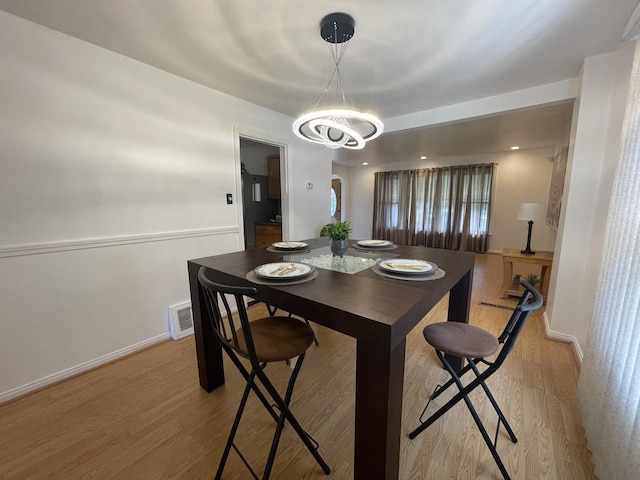 dining room featuring a chandelier, light wood-type flooring, and baseboards