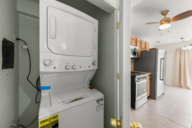 clothes washing area featuring stacked washer / dryer, ceiling fan, light tile patterned floors, and electric panel