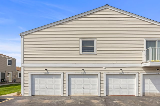 view of home's exterior with an attached garage, a balcony, and driveway