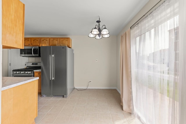 kitchen featuring stainless steel appliances, light countertops, a chandelier, hanging light fixtures, and light tile patterned floors