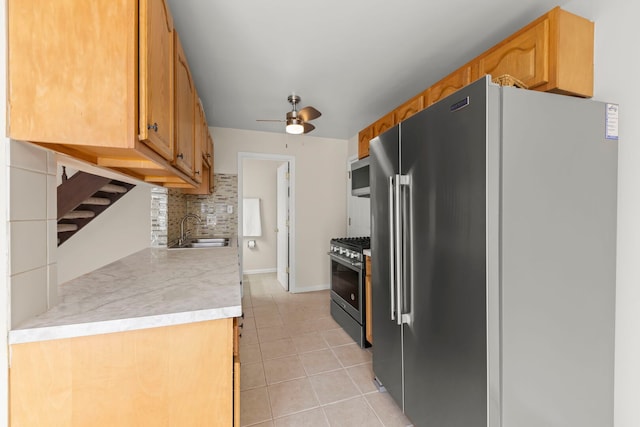kitchen with appliances with stainless steel finishes, a sink, ceiling fan, light tile patterned floors, and light countertops