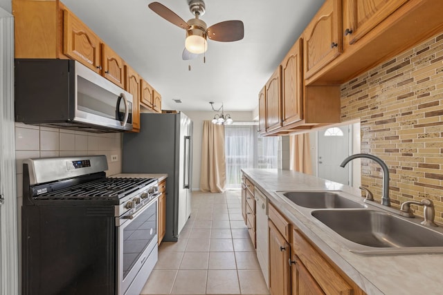kitchen featuring stainless steel appliances, a sink, tasteful backsplash, light countertops, and light tile patterned flooring