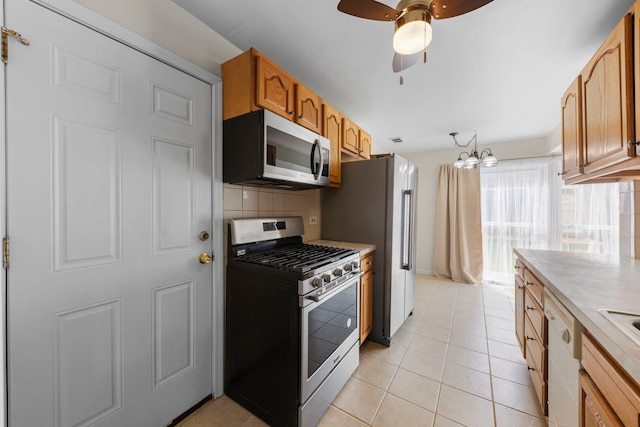 kitchen with appliances with stainless steel finishes, tasteful backsplash, light countertops, a ceiling fan, and light tile patterned flooring