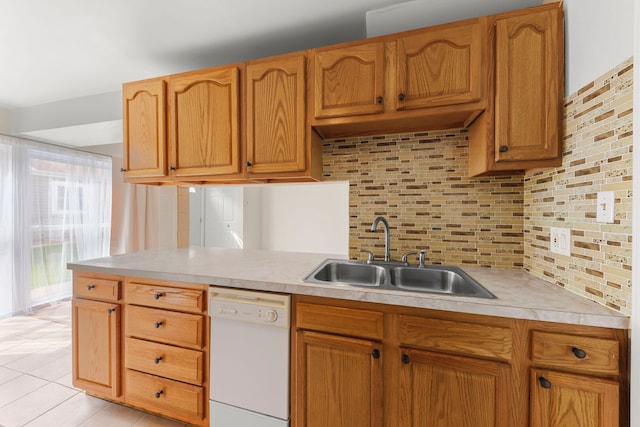 kitchen featuring white dishwasher, a sink, tasteful backsplash, light countertops, and light tile patterned floors