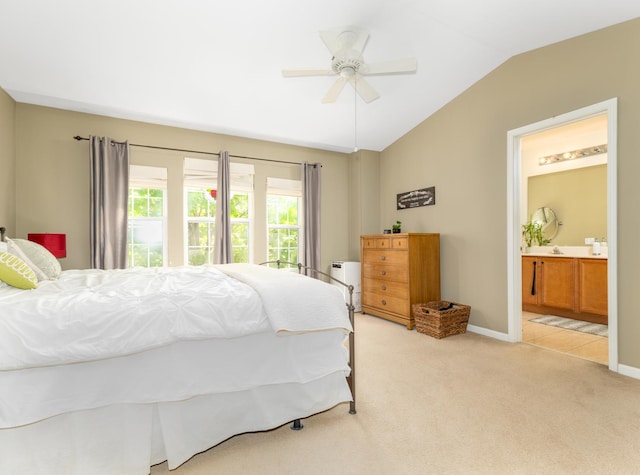 bedroom with lofted ceiling, light carpet, baseboards, a ceiling fan, and ensuite bath