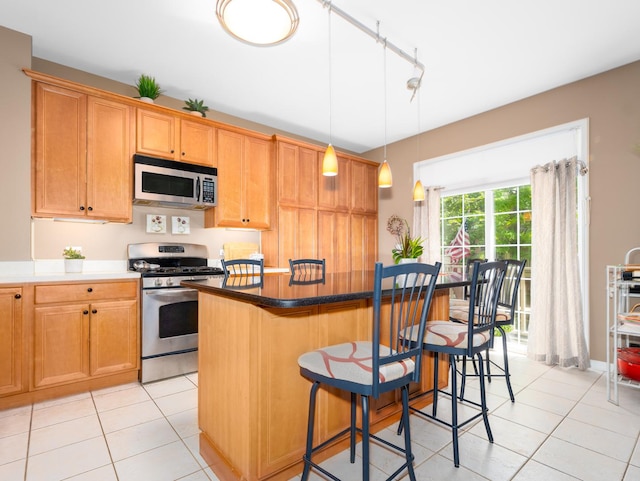 kitchen featuring appliances with stainless steel finishes, a kitchen island, a kitchen bar, and light tile patterned flooring