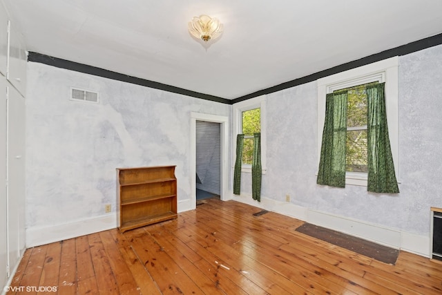 empty room featuring baseboards, hardwood / wood-style floors, and visible vents