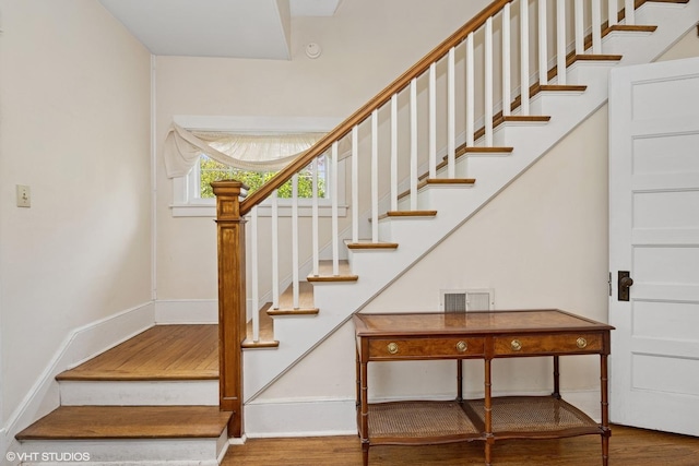 stairway with baseboards, visible vents, and wood finished floors