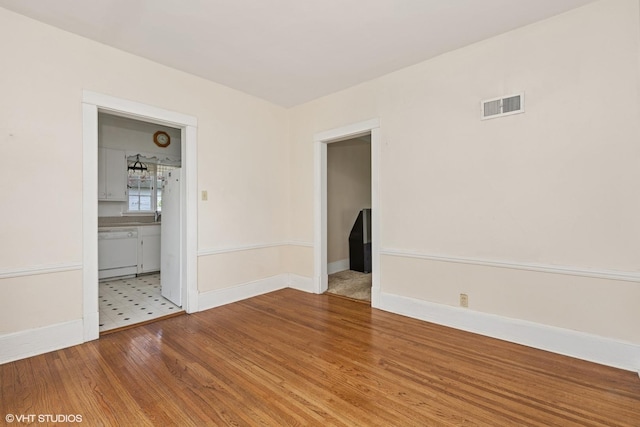 spare room featuring wood finished floors, visible vents, and baseboards