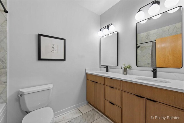bathroom with double vanity, toilet, baseboards, and a sink