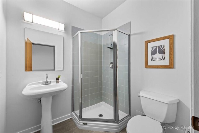 full bath featuring baseboards, a shower stall, and toilet