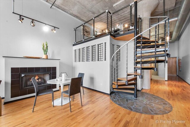 dining area with baseboards, wood finished floors, stairway, and a tile fireplace