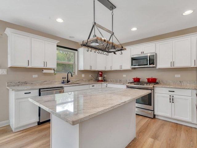 kitchen with light wood-style floors, stainless steel appliances, white cabinets, and a center island