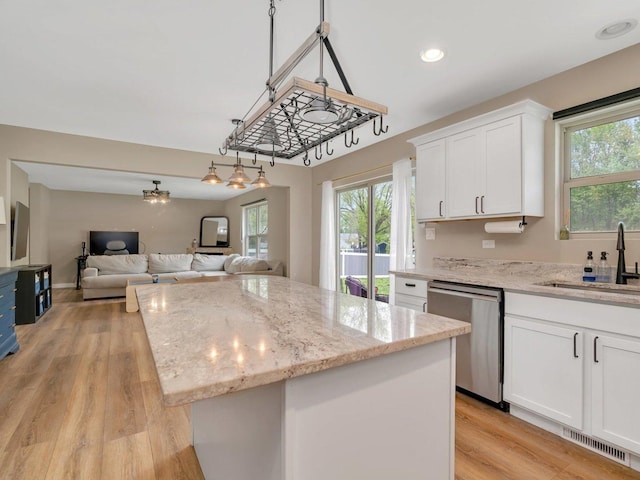 kitchen with a sink, visible vents, dishwasher, white cabinetry, and a center island