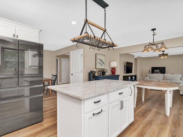 kitchen with white cabinetry, hanging light fixtures, light wood-style flooring, and a center island