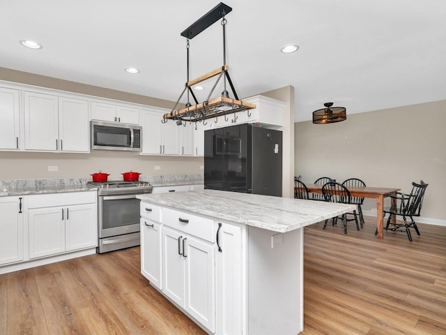 kitchen with recessed lighting, white cabinetry, a kitchen island, light wood-style floors, and stainless steel appliances