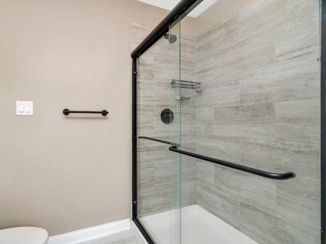 full bathroom with a shower stall, baseboards, and toilet