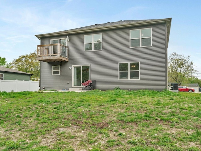 rear view of house with a yard, fence, and a balcony