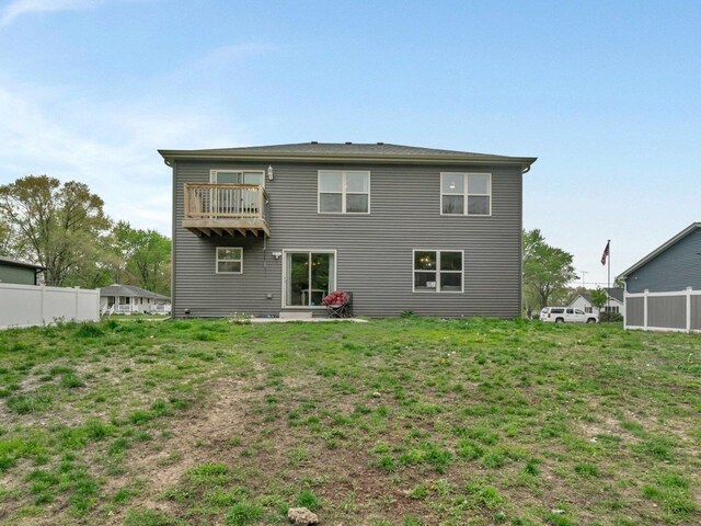 rear view of house with fence and a balcony